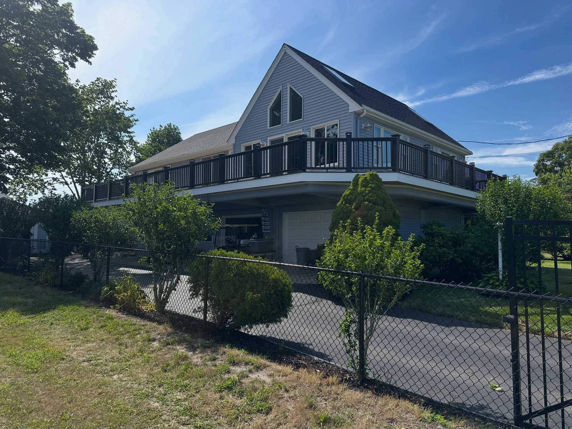 TH Finish Carpentry Instagram photograph of a gray home with a dark upper-level railing